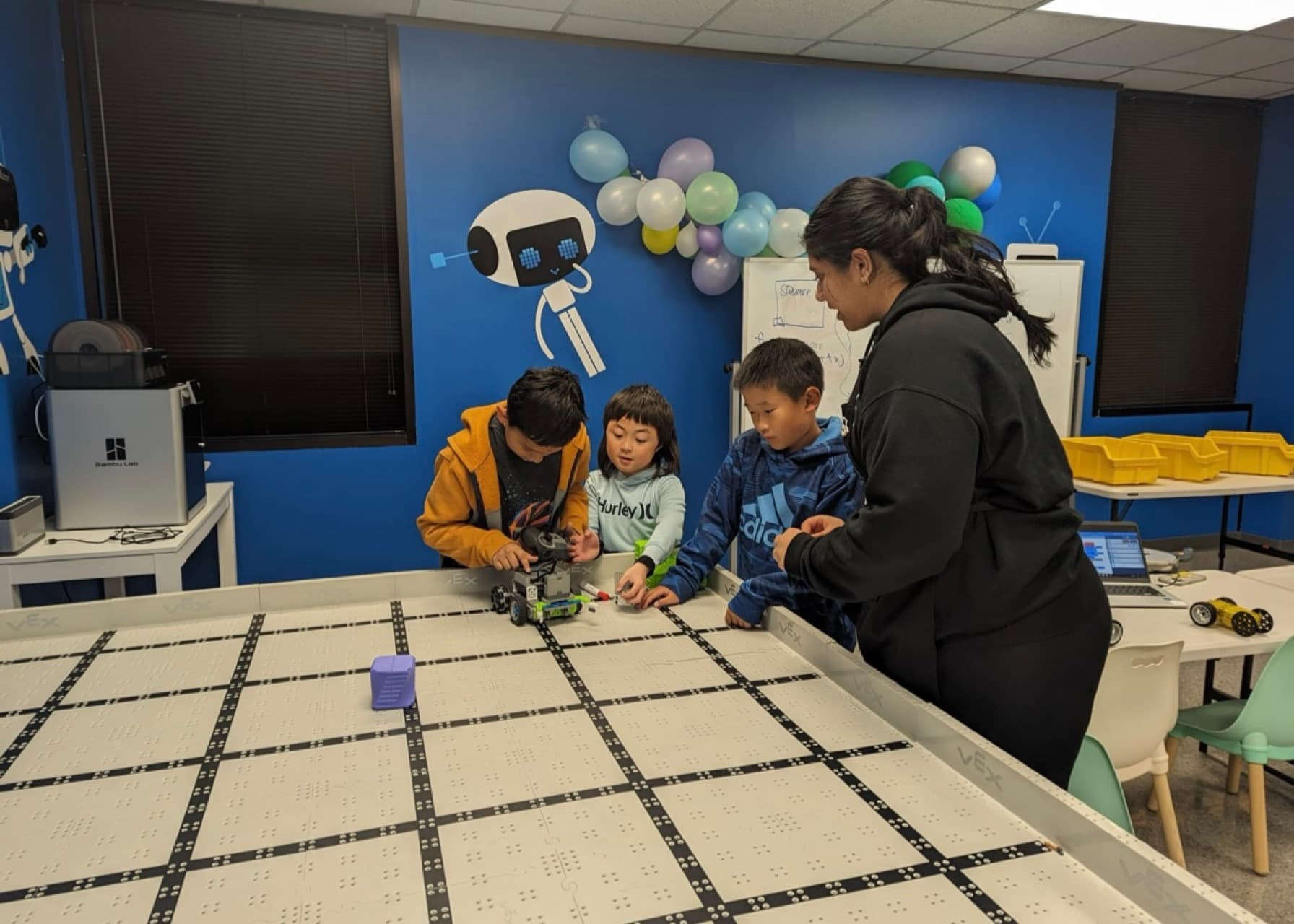 Navya coaching students building a VEX robot on a competition table