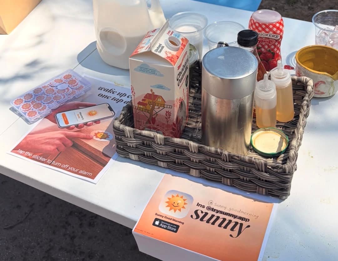 Sunny campus launch table with NFC tags, a phone showing the onboarding flow, and promo cards